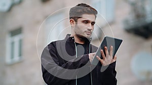 Handsome guy looking tablet screen outdoors. Young man touching digital tablet.