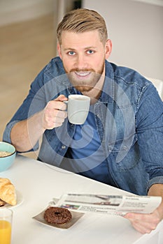 handsome guy reading newspaper and holding coffee cup