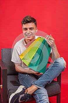 Handsome guy with shopping bags is using a mobile phone and smiling.