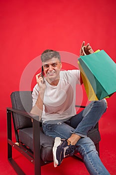 Handsome guy with shopping bags is using a mobile phone and smiling.