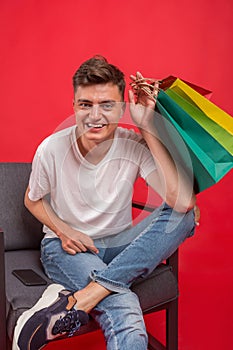 Handsome guy with shopping bags is using a mobile phone and smiling.