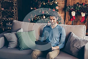 Handsome guy sit couch use computer search christmas season sales to buy fairy magic presents having house with