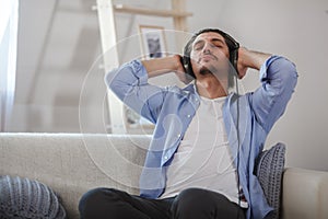 Handsome guy sitting on sofa with headphones