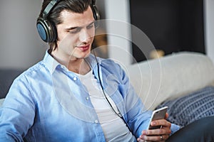 Handsome guy sitting on sofa with headphones