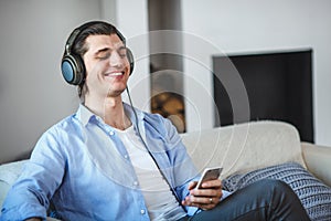 Handsome guy sitting on sofa with headphones