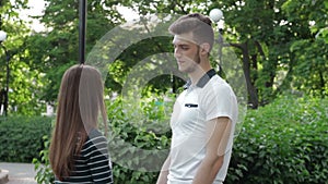 Handsome guy smiling and talking with a girl holding her hand in the Park