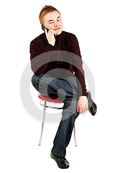 Handsome guy speaks by mobile sitting on a chair