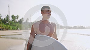 Handsome guy surfer at seaside moving to surfing with girlfriend talking and smiling. Young man surfer with surfboard