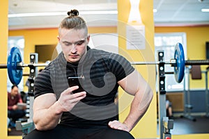 Handsome guy text messaging on his smartphone at gym.
