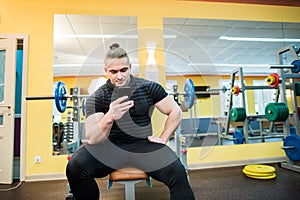 Handsome guy text messaging on his smartphone at gym.