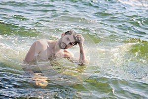 Handsome guy topless portrait in sea water