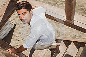 Handsome guy with trendy hairstyle going down wooden stairs while looking.