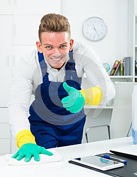 Handsome guy in uniform cleaning in office