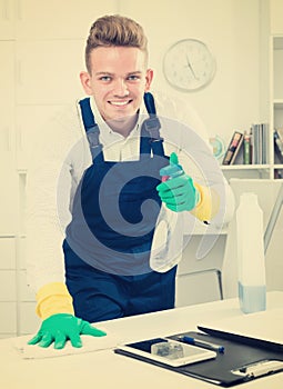 Handsome guy in uniform cleaning in office