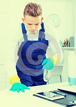 Handsome guy in uniform cleaning in office