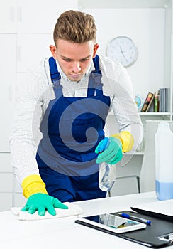 Handsome guy in uniform cleaning in office