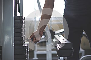 Handsome hand change weight on Iron heavy plates stacked of weight machine in gym