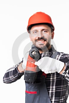 Handsome handyman in uniform with tool belt holding drill isolated on white