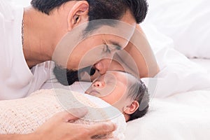 Handsome happy Asian men with beard dad kissing healthy toddler newborn baby in bed at home, Healthcare medical lifestyle father