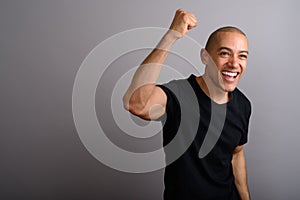 Handsome happy bald man smiling with arm raised