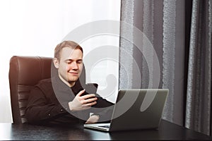 Handsome happy business man texting at his workplace