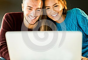 Handsome happy couple doing shopping online with laptop computer - Young people websurfing in internet on sofa at home -