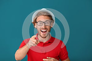 Handsome happy man pointing at viewer on color background