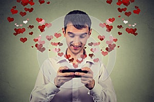 Handsome happy man sending receiving love sms text message on mobile phone