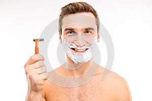 Handsome happy man with shaving foam on his face holding razor