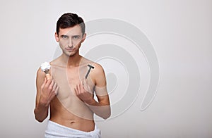 Handsome happy man with shaving foam holding razor