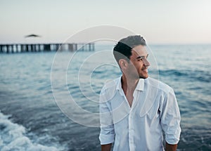 Handsome happy man wearing white shirt at the sea or the ocean b