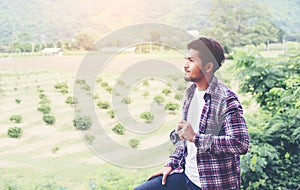 Handsome hipster bearded man with cup of morning coffee walking in park