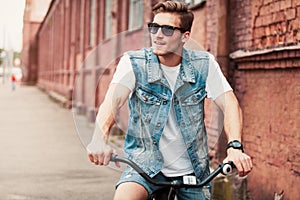 Handsome hipster enjoying city ride by bicycle.