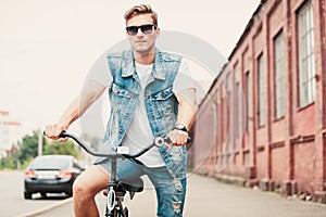 Handsome hipster enjoying city ride by bicycle.