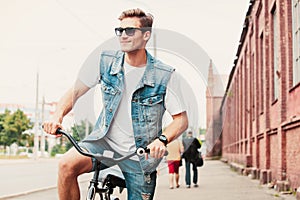 Handsome hipster enjoying city ride by bicycle.