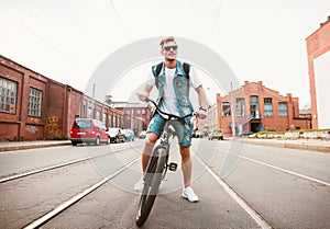 Handsome hipster enjoying city ride by bicycle.