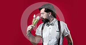 handsome hipster hold tulip bouquet. fathers day. mature retro man. bearded man in suspenders smell flowers. brutal guy