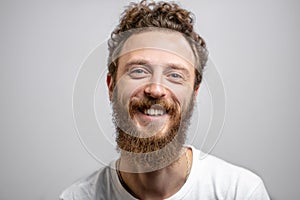 Handsome hipster man with beard smiling at camera over white background.