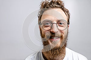 Handsome hipster man with beard smiling at camera over white background.