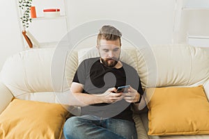 Handsome hipster man using cellphone at home. Communication leisure and technologies concept