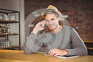 Handsome hipster phoning and holding pen