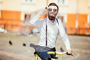 Handsome hipster in sunglasses enjoying city ride by bicycle.