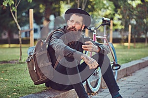 A handsome hipster traveler with a stylish beard and tattoo on his arms dressed in casual clothes and hat with a bag
