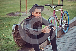 A handsome hipster traveler with a stylish beard and tattoo on his arms dressed in casual clothes and hat with a bag