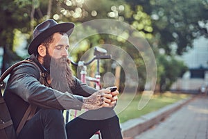 A handsome hipster traveler with a stylish beard and tattoo on his arms dressed in casual clothes and hat with a bag
