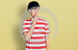 Handsome hipster young man wearing casual striped t shirt bored yawning tired covering mouth with hand