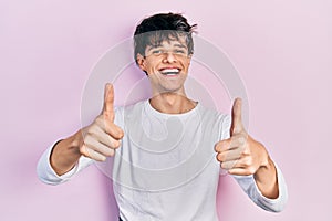 Handsome hipster young man wearing casual white shirt approving doing positive gesture with hand, thumbs up smiling and happy for