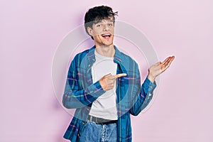 Handsome hipster young man wearing casual white t shirt and vintage shirt amazed and smiling to the camera while presenting with