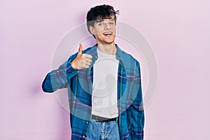 Handsome hipster young man wearing casual white t shirt and vintage shirt doing happy thumbs up gesture with hand
