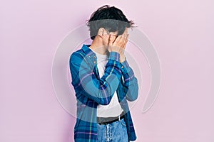 Handsome hipster young man wearing casual white t shirt and vintage shirt with sad expression covering face with hands while